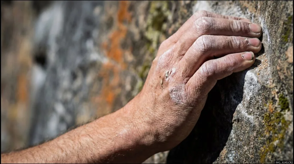 Main d'un grimpeur agrippant une fissure de roche granitique