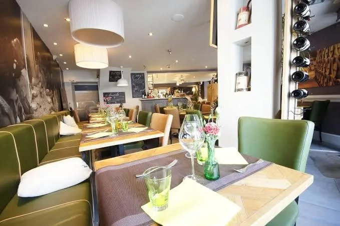 An elegant dining room with green bench seats and set tables