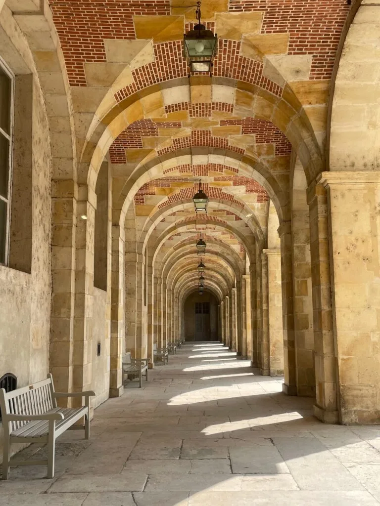 A stone-arched gallery with benches and hanging lanterns