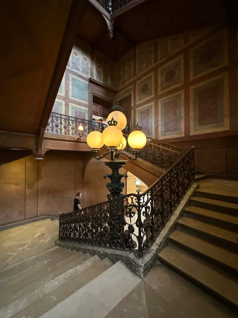 A monumental wrought-iron staircase with an antique gilded floor lamp