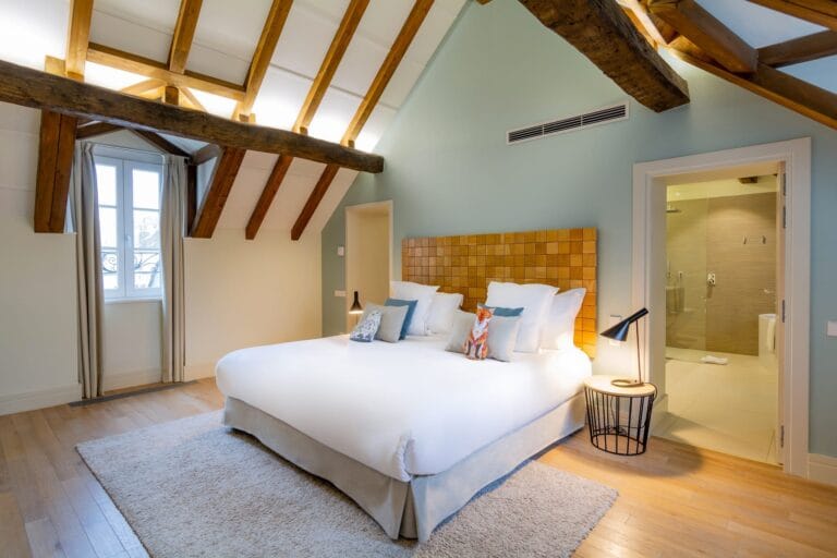 Chambre double avec lit blanc et coussins à l'Hôtel de Cavoye Fontainebleau