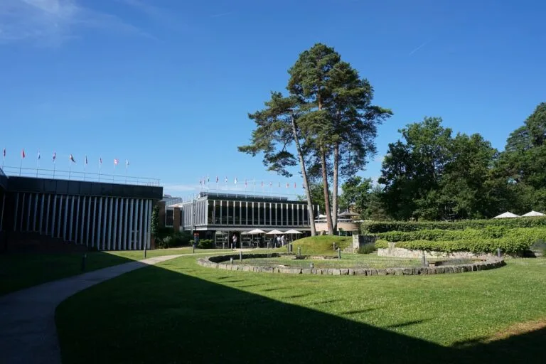 An institutional building with international flags and a lush garden