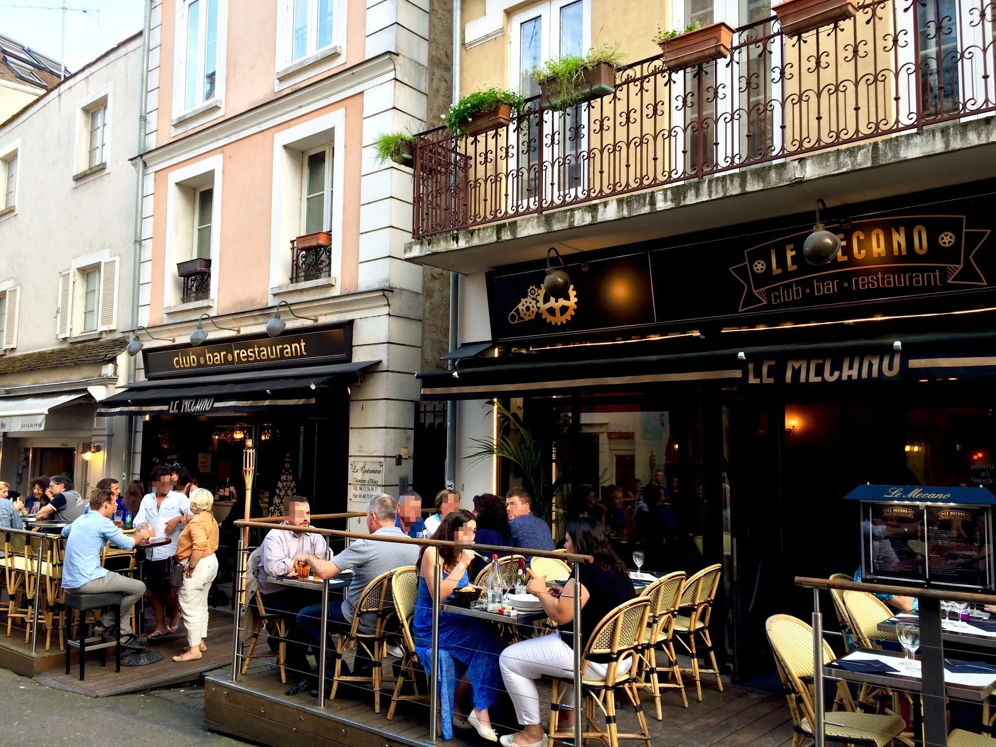 Terrasse animée du restaurant Le Mécano à Fontainebleau avec clients attablés en soirée estivale