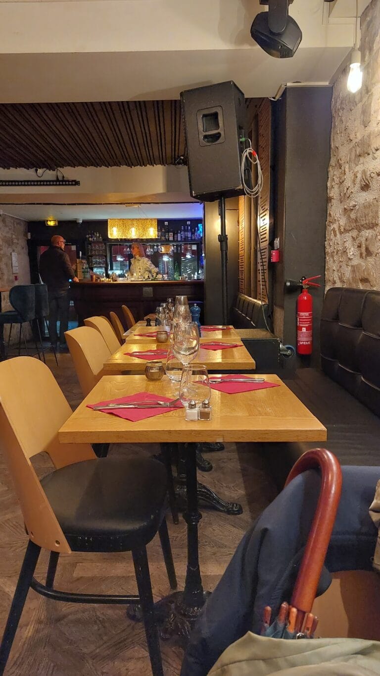 Intérieur du restaurant Le Mécano à Fontainebleau avec tables dressées aux serviettes rouges et bar en fond