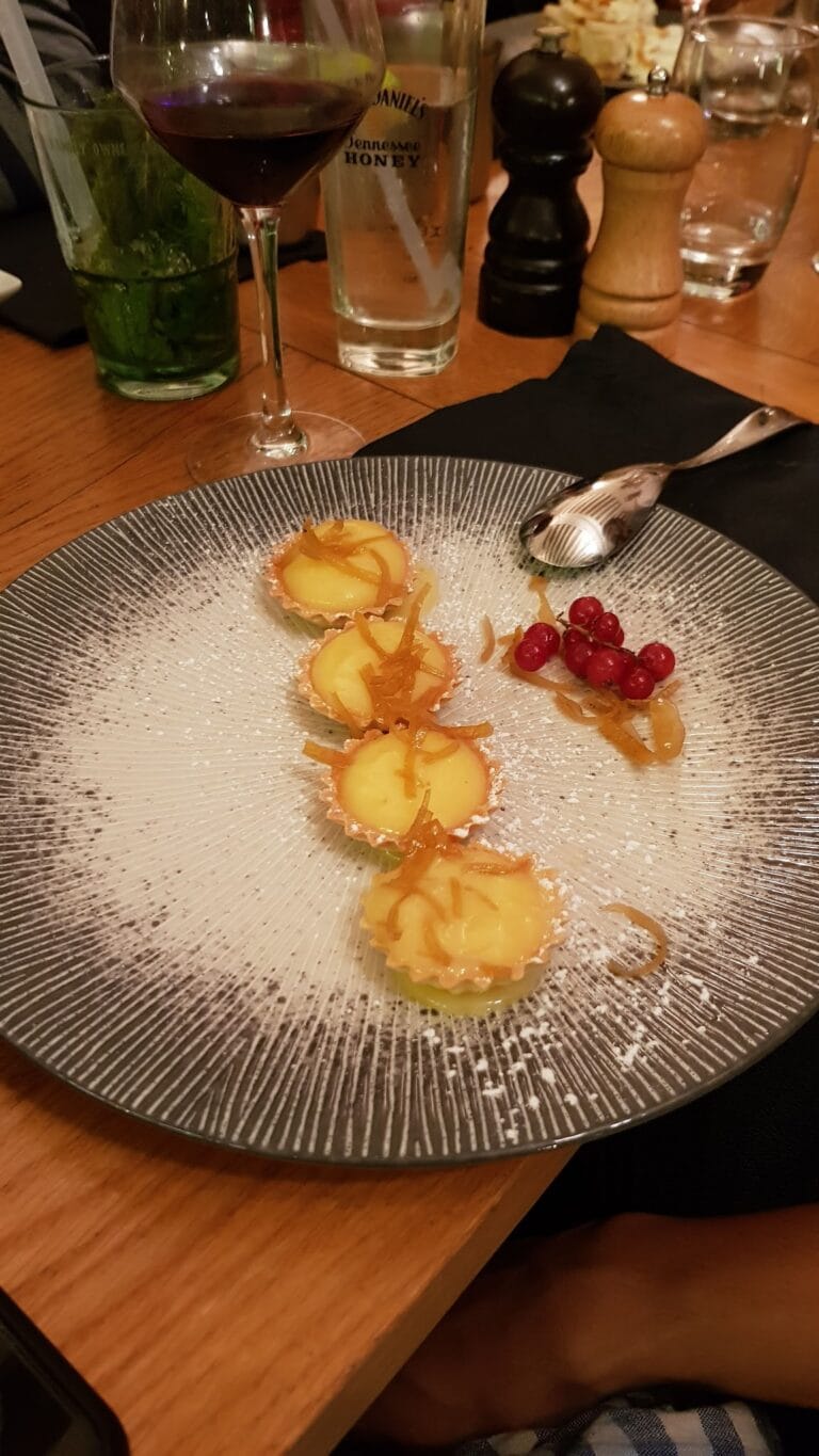 Trio de tartelettes au citron saupoudrées de sucre glace avec groseilles sur assiette grise – Le Mécano Fontainebleau