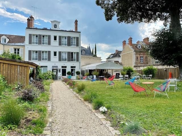 Jardin et façade de l'Hôtel Victoria Fontainebleau avec terrasse et fauteuils colorés sur la pelouse