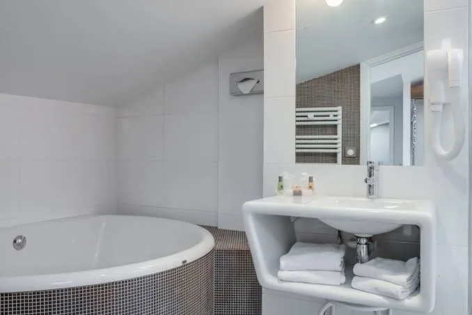 Badezimmer im Hotel Victoria Fontainebleau mit runder Mosaikbadewanne und Design-Waschbecken