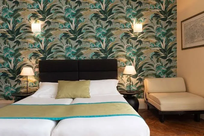 Zimmer im Hotel Victoria Fontainebleau mit Doppelbett, schwarzem Kopfteil und tropischer Tapete