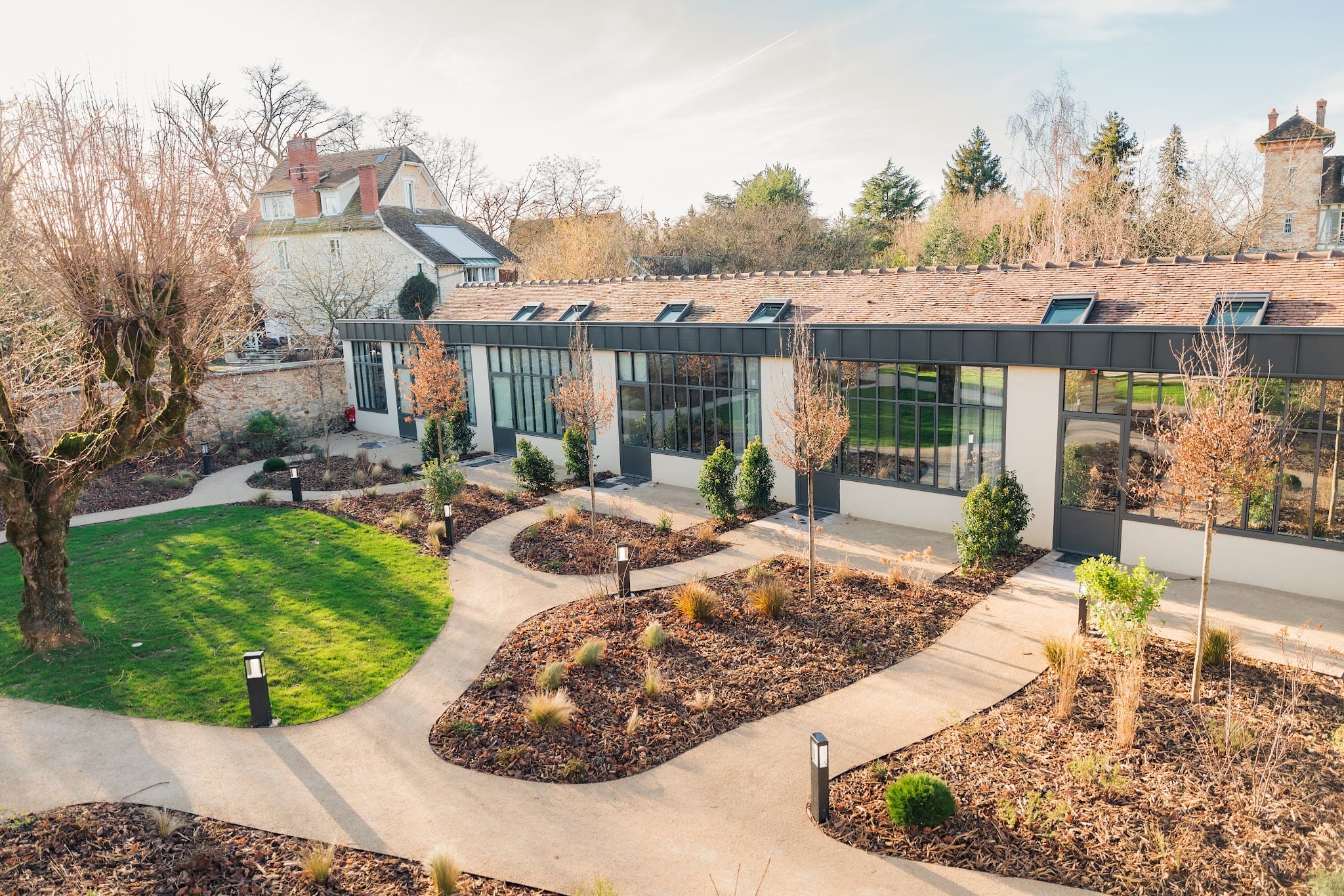 Vue aérienne du jardin de l'Esquisse Hôtel Culturel à Fontainebleau avec pelouse et aile vitrée contemporaine
