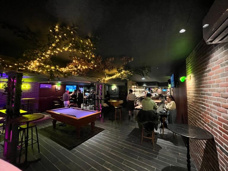Intérieur de L'Office bar à Fontainebleau de nuit, billard, guirlandes lumineuses au plafond et murs en briques