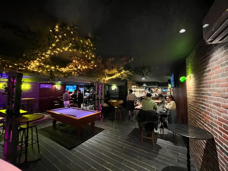 Intérieur de L'Office bar à Fontainebleau de nuit, billard, guirlandes lumineuses au plafond et murs en briques