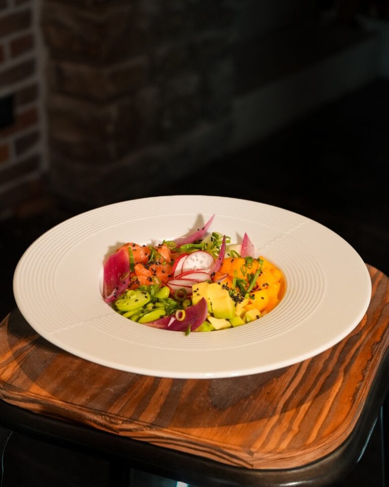 Poke bowl coloré avec thon, saumon, edamame, mangue et radis sur assiette blanche – L'Office bar à jeux de Fontainebleau