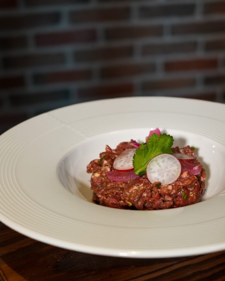Tartare de bœuf dressé en cercle avec rondelles de radis et feuilles de coriandre – L'Office bar à jeux de Fontainebleau