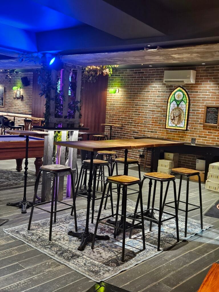 Intérieur du bar L'Office à Fontainebleau avec hautes tables, murs en briques et billard
