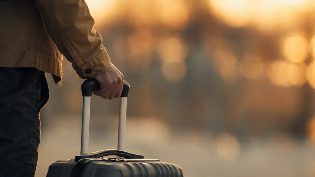 Voyageur tenant une valise à roulettes au coucher du soleil