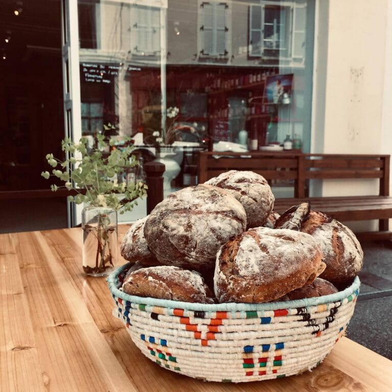Basket of artisan breads in a colourful basket on the wooden counter at Maison Sumac