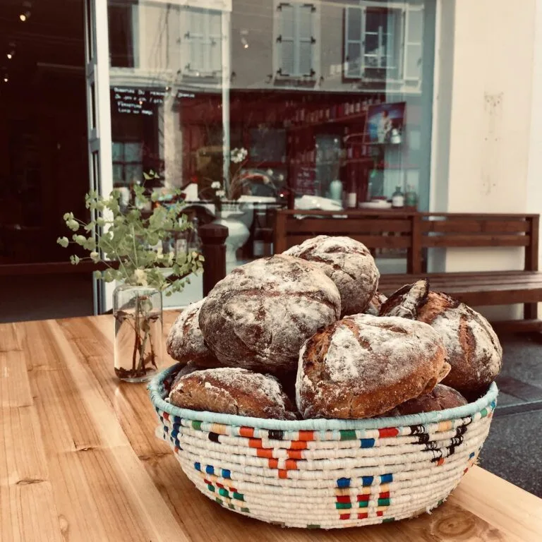 Basket of artisan breads in a colourful basket on the wooden counter at Maison Sumac