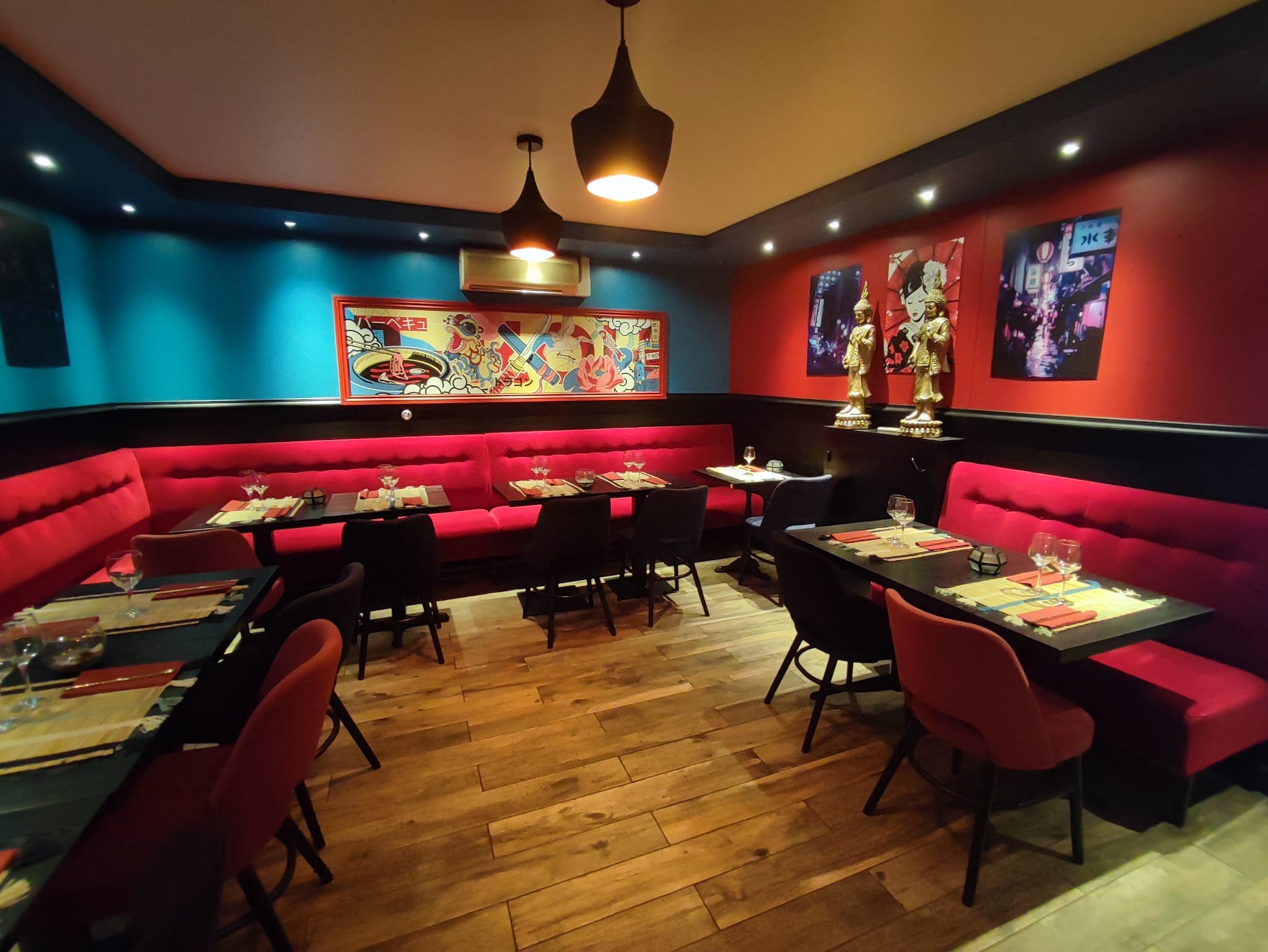 Salle intérieure du restaurant T Koh à Fontainebleau, banquettes rouges, décoration asiatique colorée et statuettes dorées
