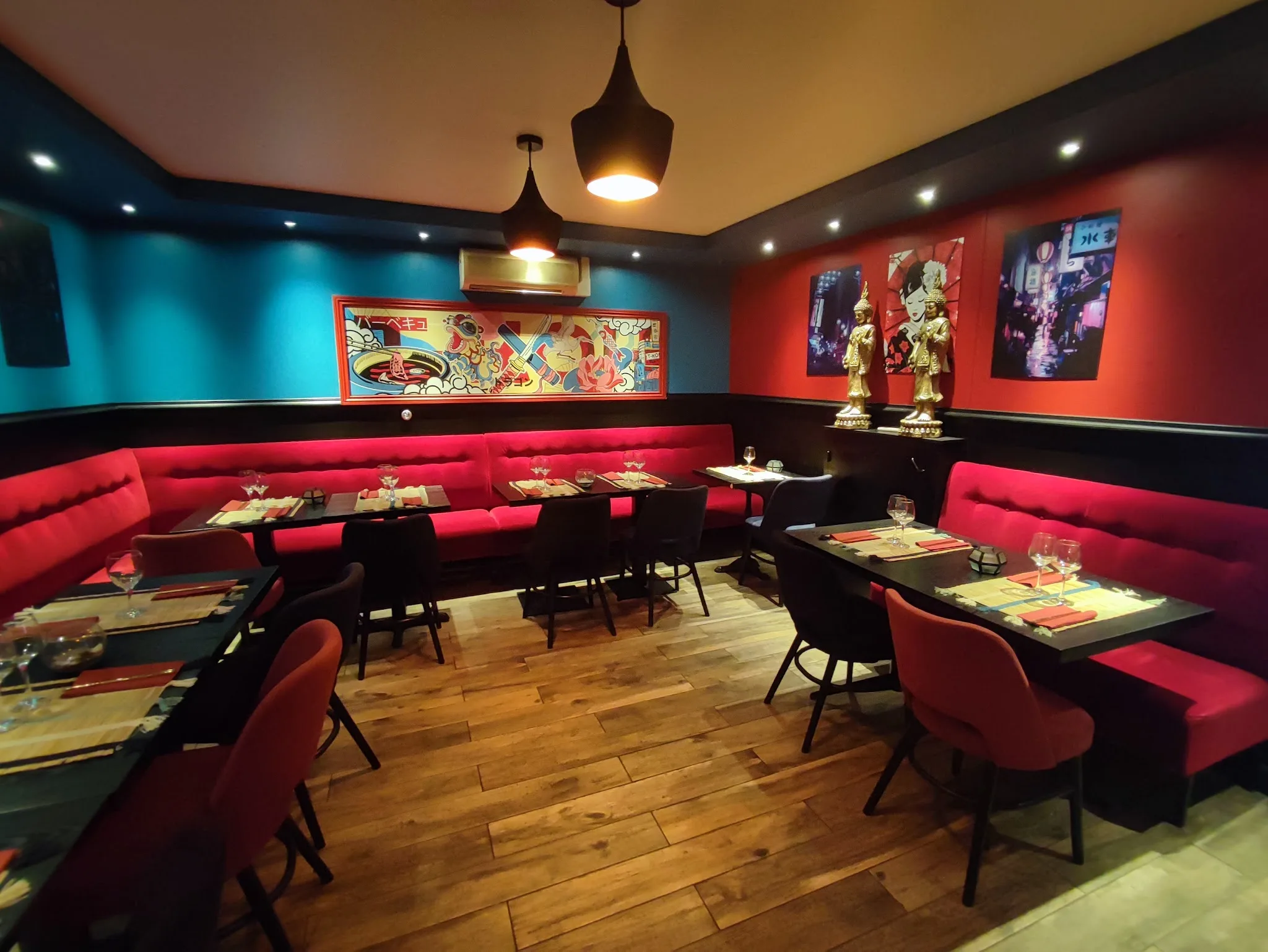 Salle intérieure du restaurant T Koh à Fontainebleau, banquettes rouges, décoration asiatique colorée et statuettes dorées