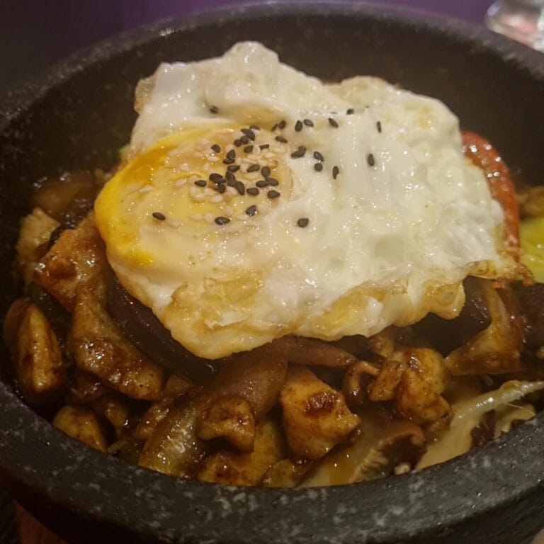 Bibimbap in einer heißen Steinschale mit Spiegelei und Sesamkörnern serviert bei T Koh
