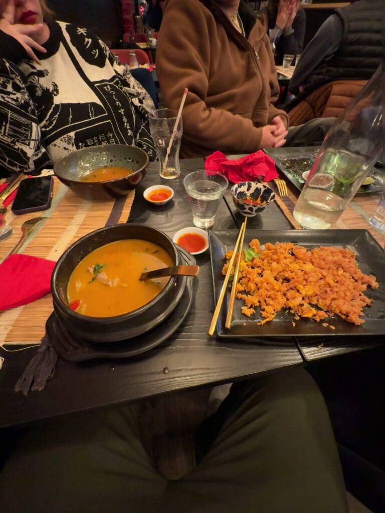 Thai-Curry im Topf serviert mit gebratenem Reis auf schwarzem Teller, Abendstimmung im Restaurant