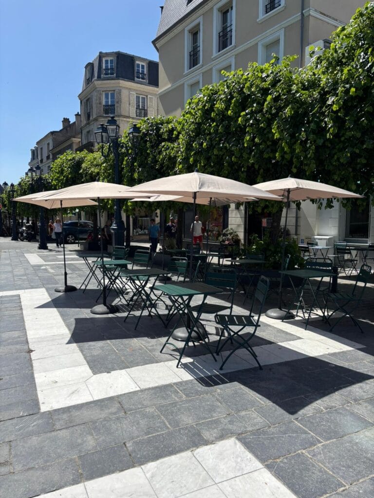French café terrace with beige parasols in direct sunlight