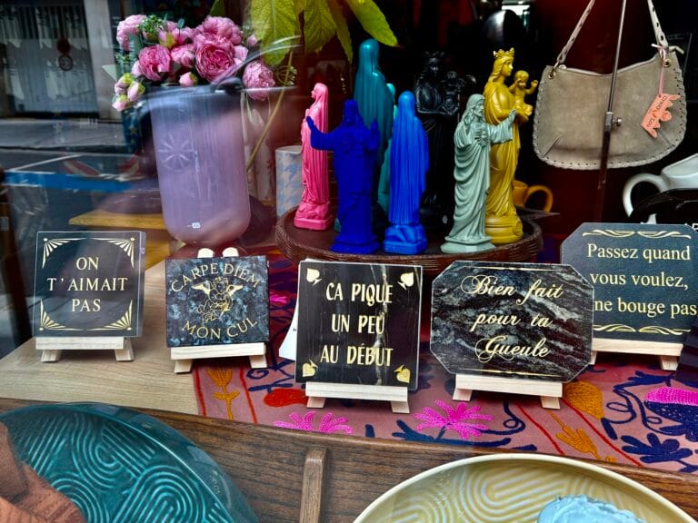 Maison Madeleine’s shop window in Fontainebleau, featuring figurines and humorous plaques